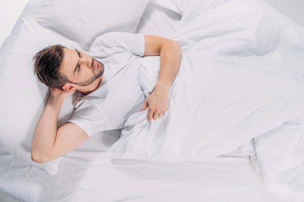 istock overhead view of pensive bearded man looking away while resting in bed 946063950