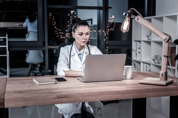 istock Concentrated cute doctor sitting and working with the laptop. 946072442