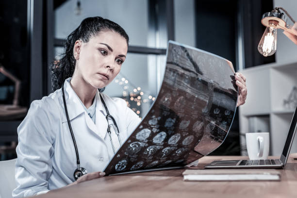 istock Serious busy medic holding and overlooking x-ray scan. 946072574