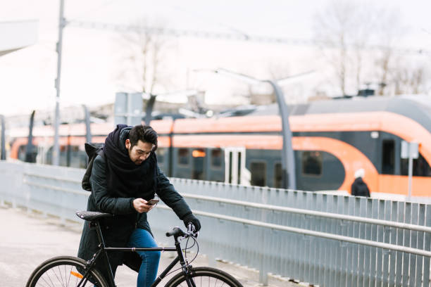 istock Asian man with bicycle in railroad station using smartphone 946073060