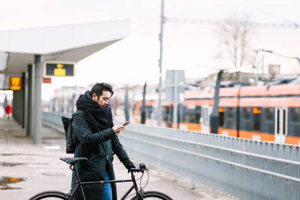 istock Asian man with bicycle in railroad station using smartphone 946075144