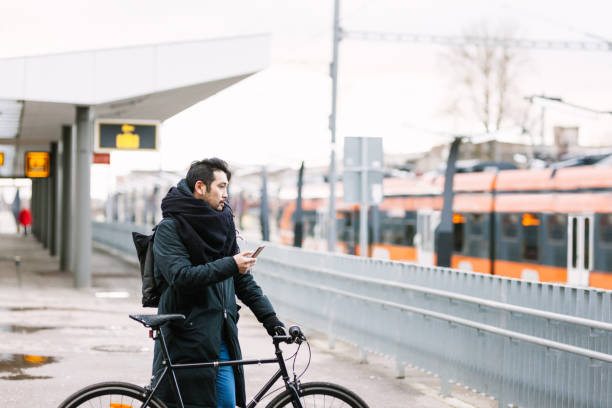 istock Asian man with bicycle in train station using smartphone 946075196