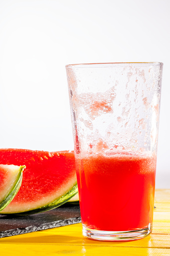 Cooling summer fruit drink. Watermelon smoothie. Thirst quenching iced crush with fresh watermelon slices. White background with copy space.