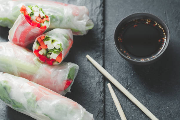 istock Asian fresh spring rolls. Raw cucumber, carrot, lettuce, bell pepper, tofu cheese inside rice paper. The concept of healthy and vegan food. Top view. 946092182