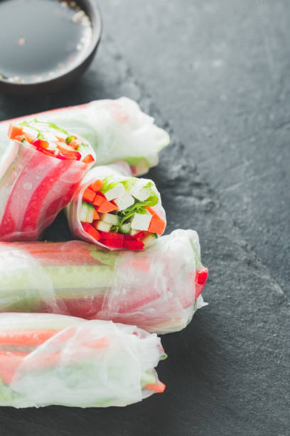 istock Asian fresh spring rolls. Raw cucumber, carrot, lettuce, bell pepper, tofu cheese inside rice paper. The concept of healthy and vegan food. 946092204