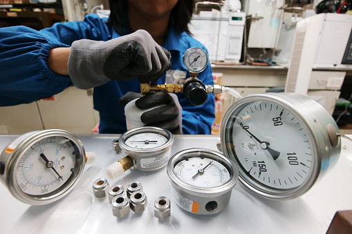 Instrument technician is fixing pressure guages. Engineer check and repair pressure guages on the table.