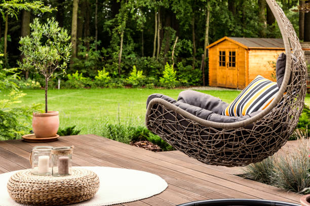Hanging chair in the garden Pouf on white round rug next to hanging chair in the garden of house garden lights candle stock pictures, royalty-free photos & images