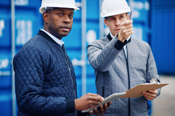 istock Engineers disucssing shipping logistics while standing in a dockyard 946119662