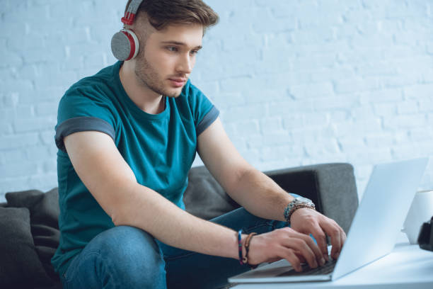 istock focused young man in headphones using laptop at home 946120086