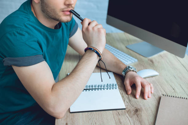istock cropped shot of young man holding pen and taking notes while working at home 946139648
