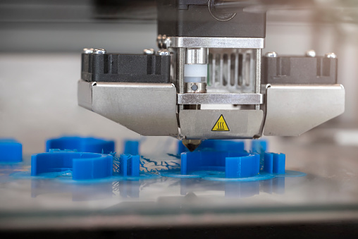 A 3D printer printing prototypes in a biomedical classroom laboratory, close up view.