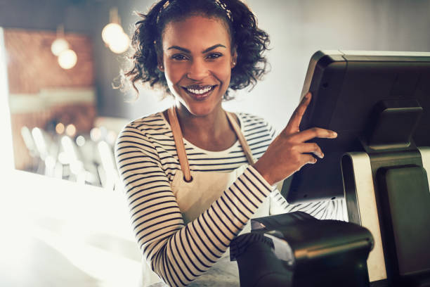 Smiling young African waitress working in a trendy restaurant stock photo