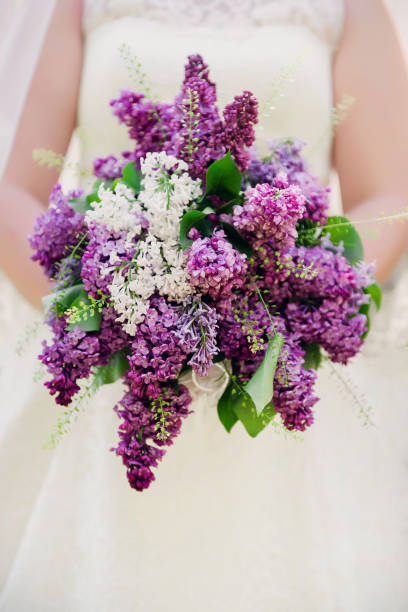 istock Bride holding a bouquet from lilac. Bride with bouquet, closeup 946165418