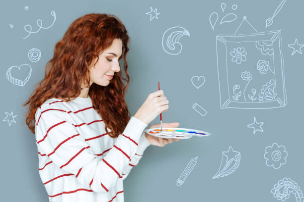 istock Smiling painter looking calm while mixing colors and smiling 946174132
