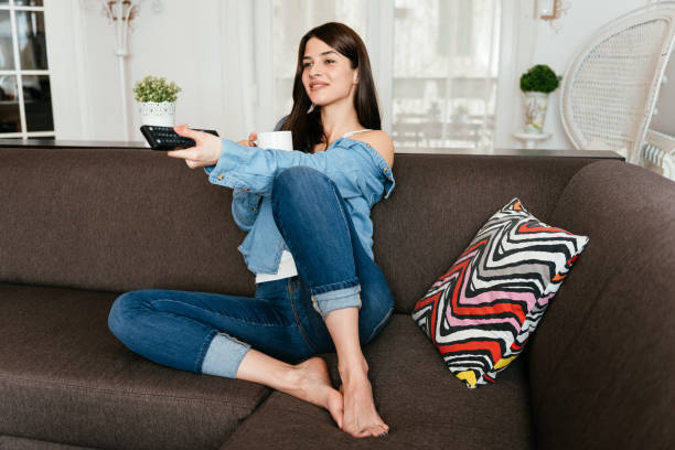 istock Smiling young woman watching TV at home 946181542
