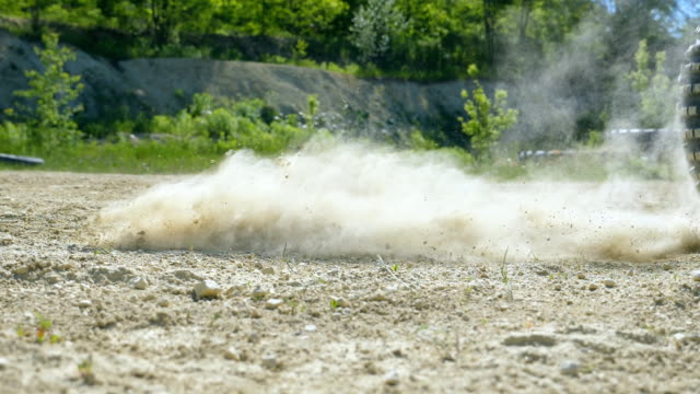 Wheel of motocross bike starting to spin and kicking up ground or dirt. Motorcycle starts the movement. Slow motion Close up Low angle view Side view