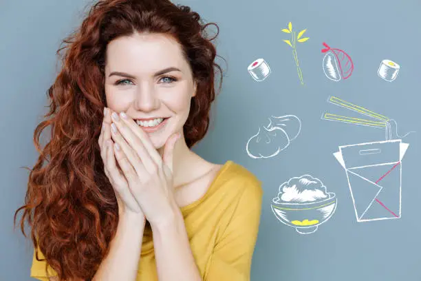 Photo of Positive student smiling while seeing unusual food in the restaurant