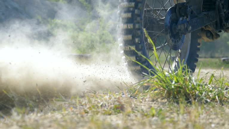 Studded wheel of motocross bike starting to spin and kicking up ground or dirt. Motorcycle starts the movement. Slow motion Close up Rear back view Low angle view