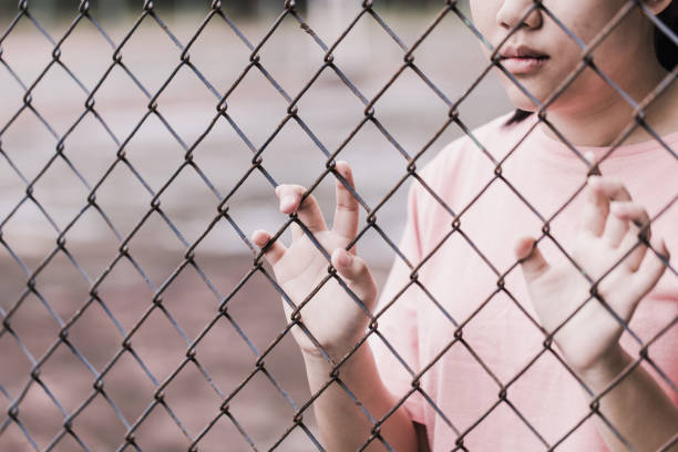 teen behind the cage or woman jailed, unhappy girl hand sad hopeless at fence prison in jail, no free and freedom struggle teen concept. teen behind the cage or woman jailed, unhappy girl hand sad hopeless at fence prison in jail, no free and freedom struggle teen concept. corral photos stock pictures, royalty-free photos & images