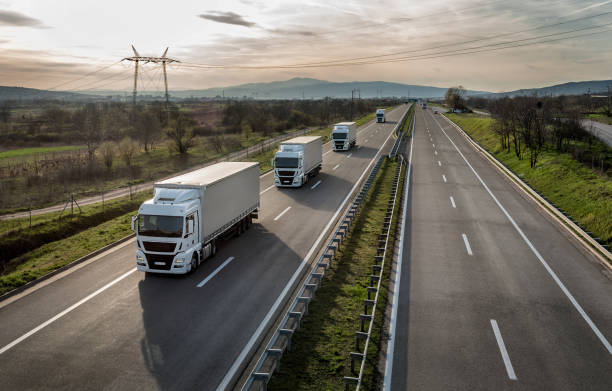 caravan of konvooi van vrachtwagens op de snelweg - vervoer stockfoto's en -beelden