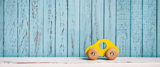 Wooden, yellow toy car on white shelf and blue planks Wooden, yellow toy car on white shelf and blue planks wooden car stock pictures, royalty-free photos & images