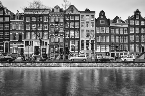 Cityscape, black-and-white - evening view of the houses with festive decorations and the city channel with boats, city of Amsterdam, The Netherlands