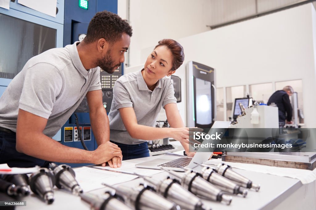 Two Engineers Using CAD Programming Software On Laptop Manufacturing Stock Photo