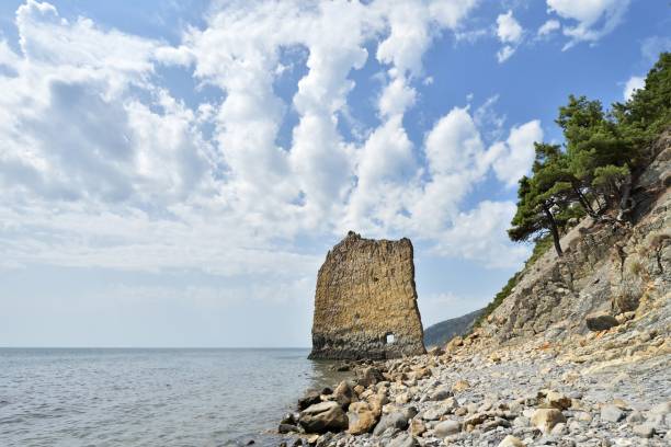 una roccia bella e insolita nel mare, verticale, piatta e alta, accanto a una costa rocciosa. il suo nome "sail" in lingua russa "parus" - beauty in nature cloud rocky coastline rock foto e immagini stock