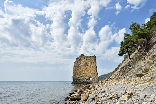 A beautiful and unusual rock in the sea, vertical, flat and high, next to a rocky shore. Her name "Sail" in Russian language "Parus" A beautiful and unusual rock in the sea, vertical, flat and high, next to a rocky shore. Her name "Sail" in Russian language "Parus". Located near the city of Gelendzhik in the village of Praskoveevka. krasnodar krai stock pictures, royalty-free photos & images