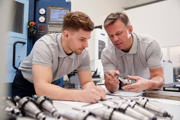 engineer showing apprentice how to measure cad drawings - trainee imagens e fotografias de stock