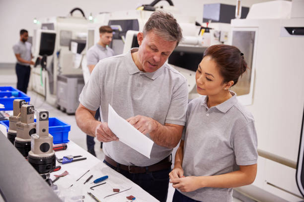 istock Engineer And Female Apprentice Discussing Job Sheet In Factory 946237282