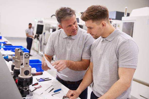 istock Engineer And Apprentice Discussing Job Sheet In Factory 946237292