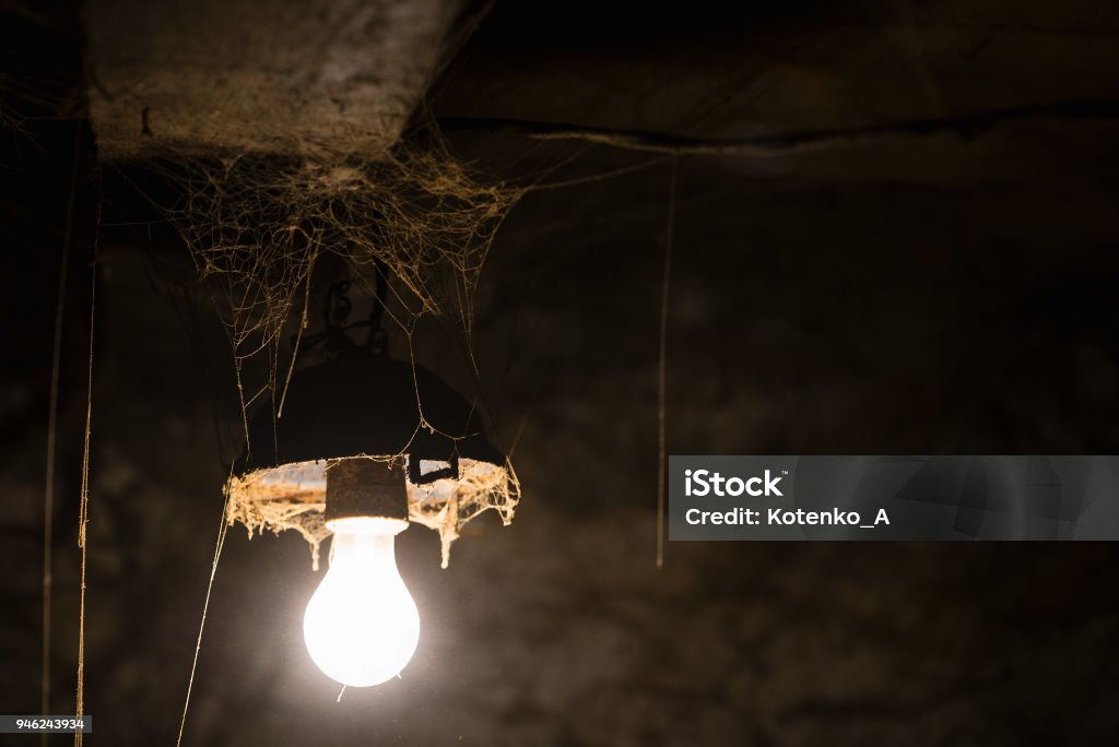 Glowing lamp in a barn Glowing lamp in a dirty barn. Old web Shed Stock Photo