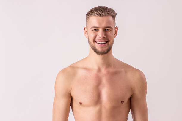 Handsome naked hipster man isolated Portrait of handsome shirtless man looking to camera and smiling while standing isolated on white background. Young bearded hipster standing naked. Muscular and masculine man. Perfect men's beauty semi dress stock pictures, royalty-free photos & images