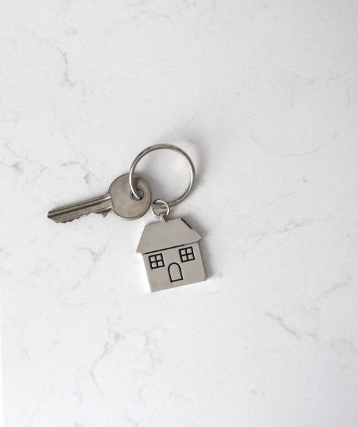 New Home A key and key ring of a home resting on a marble kitchen counter house key stock pictures, royalty-free photos & images