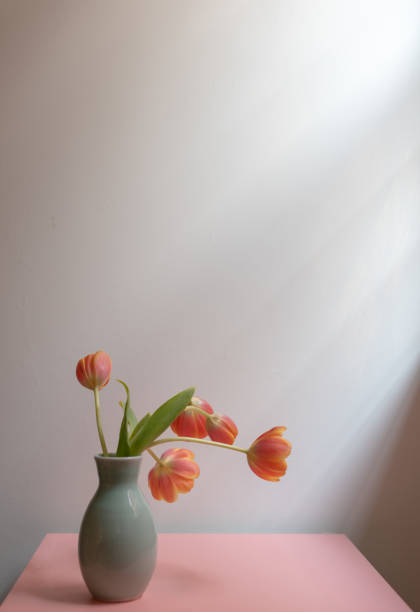 istock Orange tulips in green vase on pink table 946327822