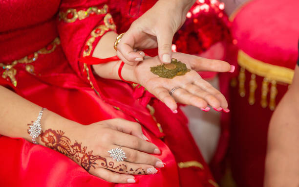 istock Female hands decoratively colored by henna with cup . Hold a bowl with coconut under her hands . Mixing henna for hair. Natural henna color mixed pasted in a bowl. Coin money 946327870