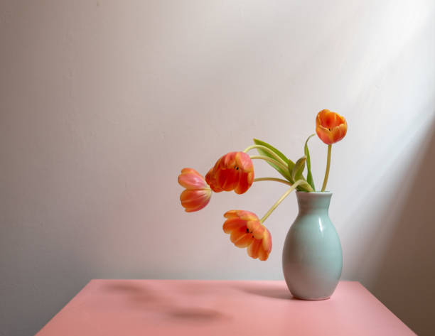 istock Orange tulips in green vase on pink table 946328056