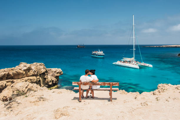 A couple sits on a bench and looks at the lagoon stock photo