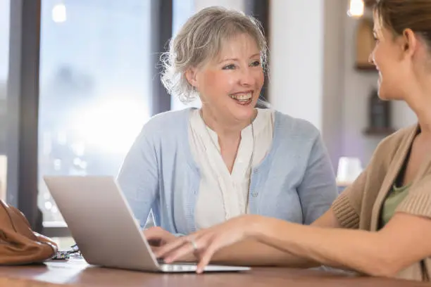 Photo of Senior woman and her daughter use computer together