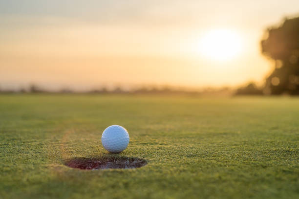 A golf ball near miss on the edge of going in the hole on the putting green.