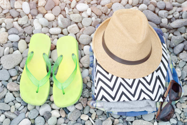 istock Flip-flops,  hat and clothes on pebbles. Travel concept 946365924