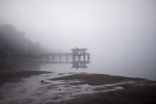 Quiet scene of a small building on a pier surrounded by fog. Shot near Point Reyes, California.