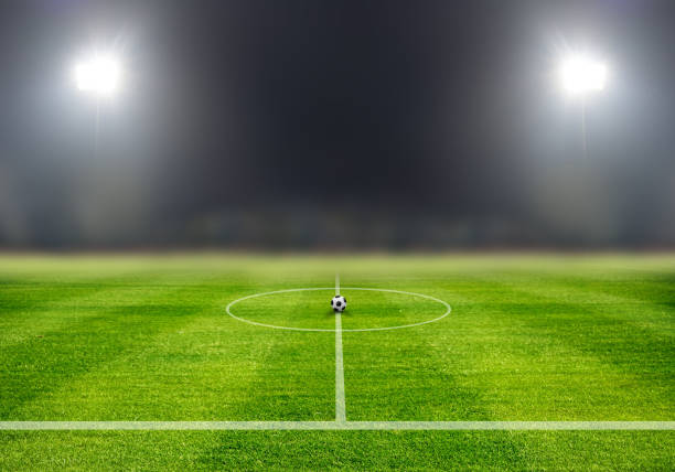 soccer ball on center soccer field in night with spotlight, game start concept