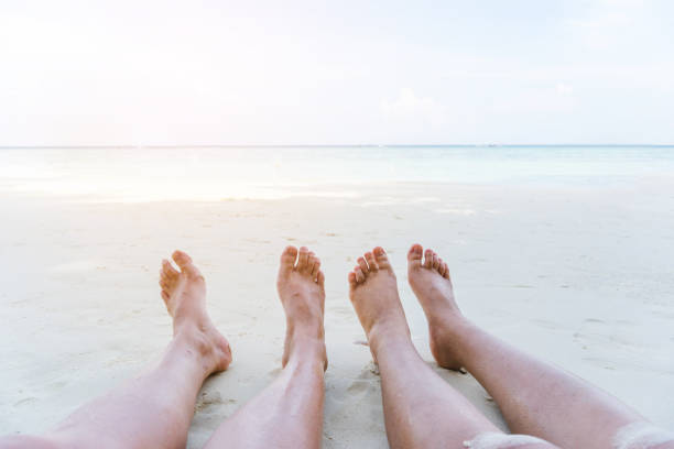 ビーチでリラックスした夏の休暇のカップル - flip flop human foot sand women ストックフォトと画像