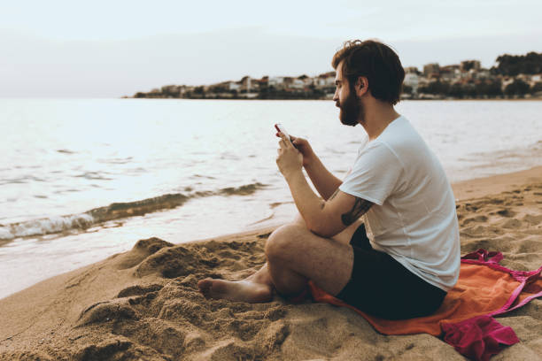 istock Handsome man using phone on the beach on a summer day 946409020
