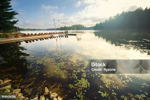 Adirondack And Lounge Chairs Sitting On A Dock On A Lake Stock Photo - Download Image Now