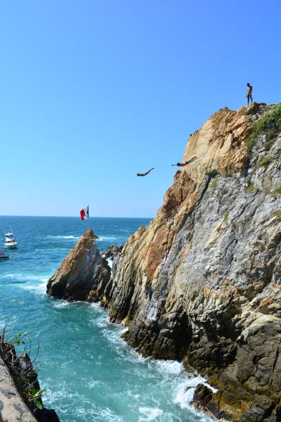 Acapulco, Mexico - December 22, 2011: A cliff diver is seen in the air, jumping to the water from the cliff at La Quebrada, for the daily night performance.