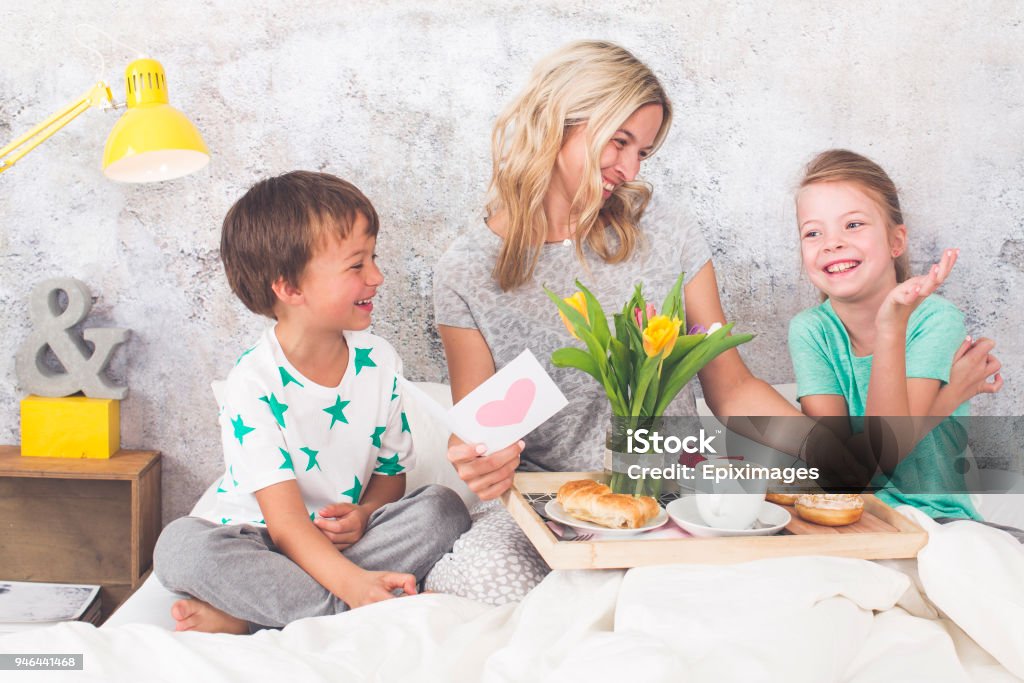 Mother´s jour - deux enfants surprennent leur mère avec petit déjeuner au lit moderne - Photo de Fête des mères libre de droits