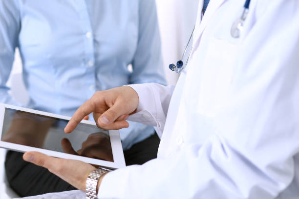 istock Male doctor using touchpad or tablet computer while consulting female patient in hospital. Medicine and healthcare concept 946448486